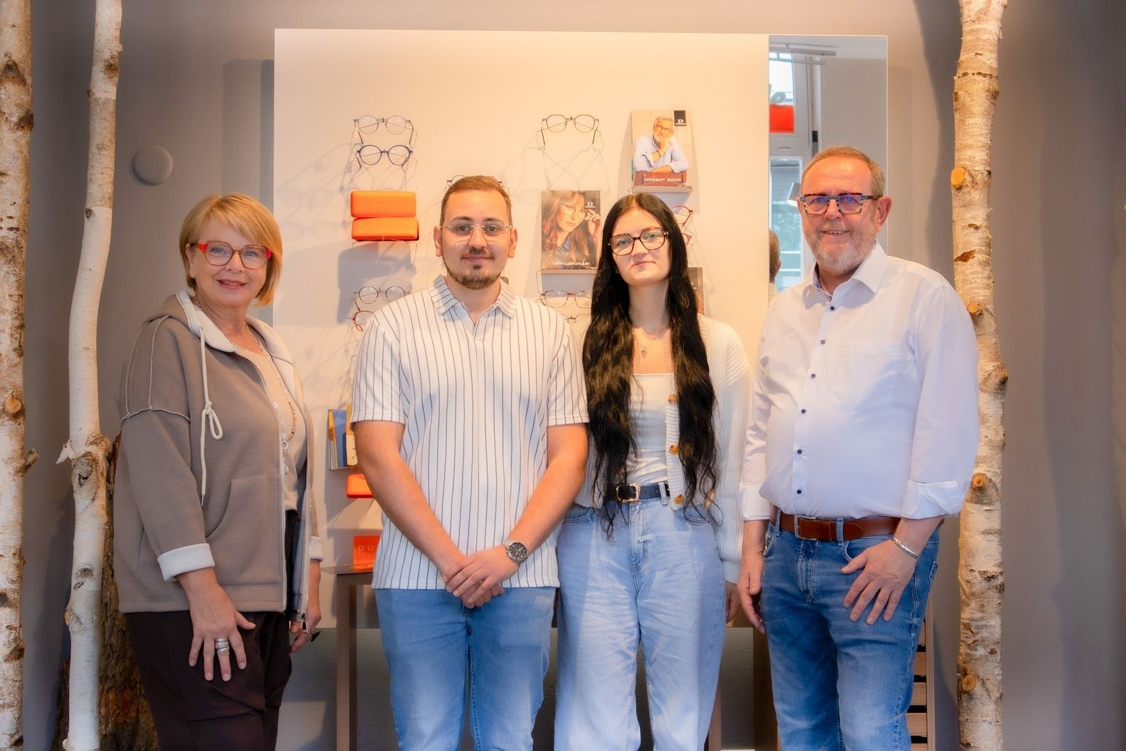Vier Menschen stehen vor einer Auswahl an Brillen